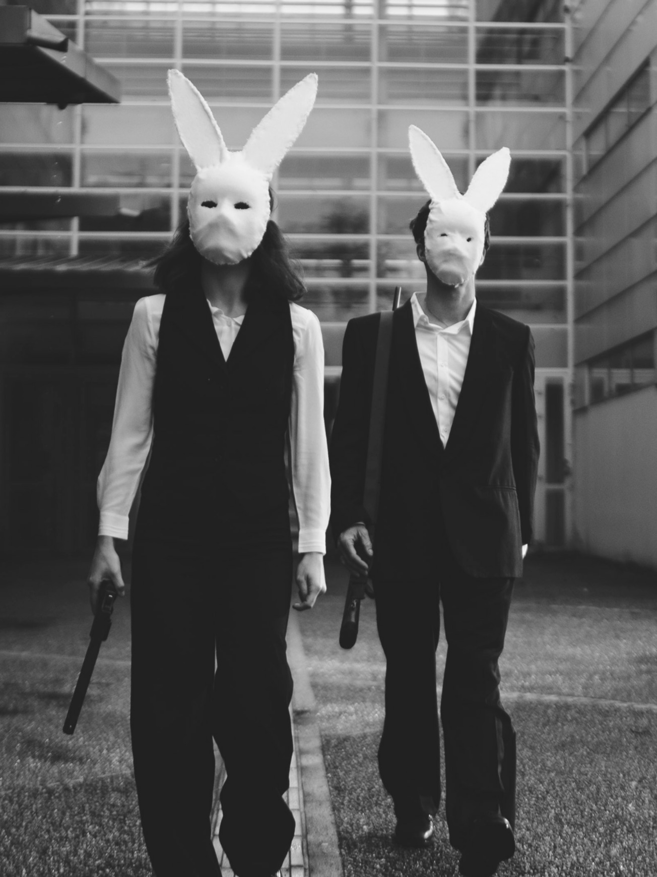 Deux comédiennes en costume sombre dans un hangar, en noir et blanc